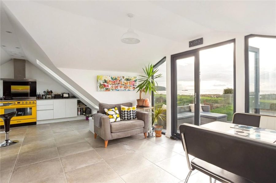 Open-plan loft living space with a sloped ceiling, kitchen area and glazed doors to a balcony