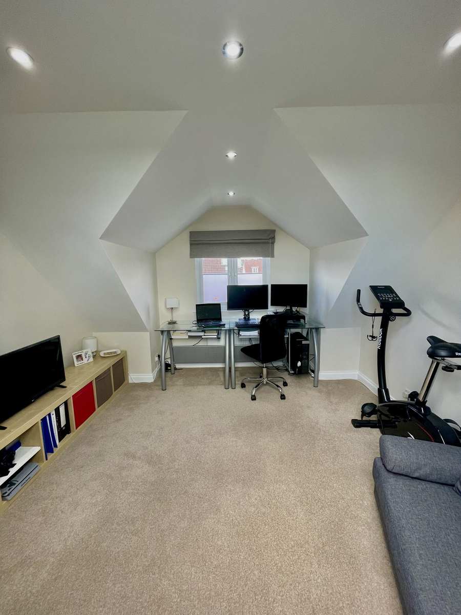 Loft converted into a home office and gym under a vaulted ceiling